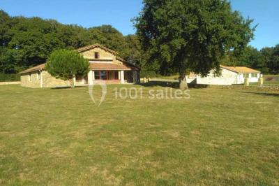 Chemin de gravier bordé de murets en pierre, menant à un paysage rural avec champs et arbres.