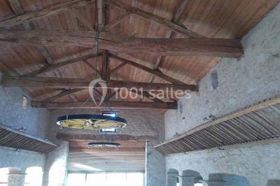 Chemin de gravier bordé de murets en pierre, menant à un paysage rural avec champs et arbres.