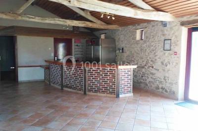 Chemin de gravier bordé de murets en pierre, menant à un paysage rural avec champs et arbres.