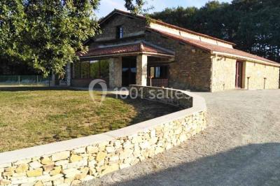 Chemin de gravier bordé de murets en pierre, menant à un paysage rural avec champs et arbres.