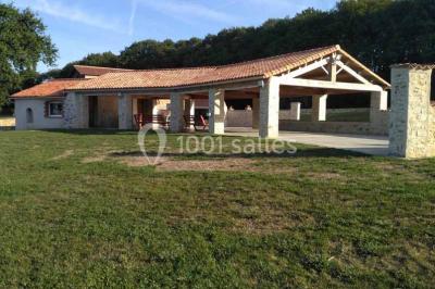 Chemin de gravier bordé de murets en pierre, menant à un paysage rural avec champs et arbres.