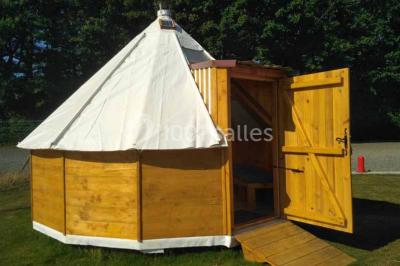 Chemin de gravier bordé de murets en pierre, menant à un paysage rural avec champs et arbres.