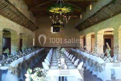 Chemin de gravier bordé de murets en pierre, menant à un paysage rural avec champs et arbres.