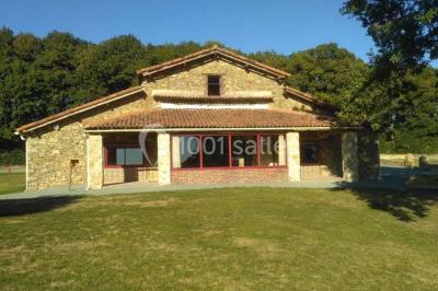 Chemin de gravier bordé de murets en pierre, menant à un paysage rural avec champs et arbres.