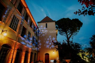 Un couple danse sous des guirlandes lumineuses devant un bâtiment éclairé en rouge, de nuit.