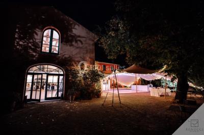 Un couple danse sous des guirlandes lumineuses devant un bâtiment éclairé en rouge, de nuit.