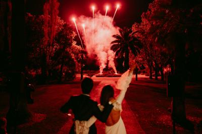 Un couple danse sous des guirlandes lumineuses devant un bâtiment éclairé en rouge, de nuit.