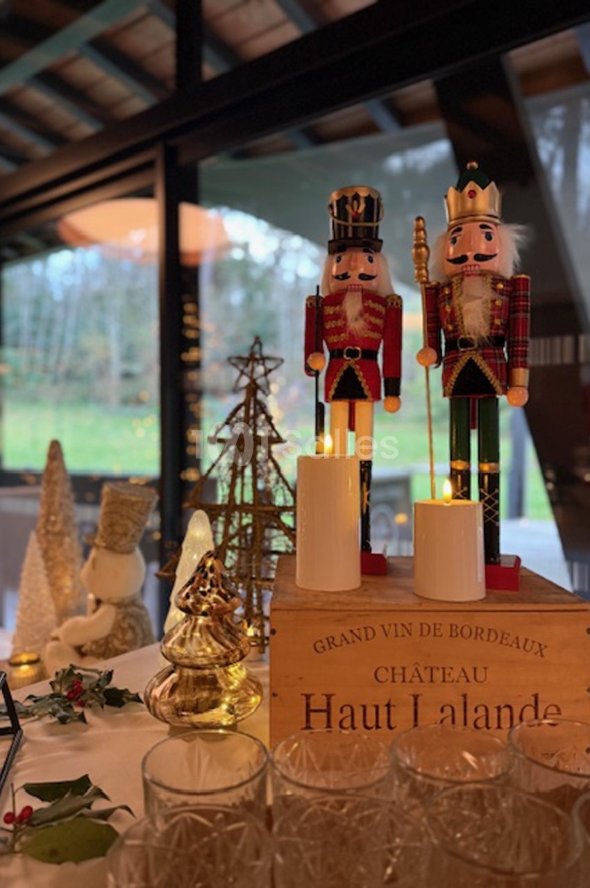 Deux casse-noisettes décoratifs posés sur une caisse de vin, entourés de bougies et décorations de Noël.
