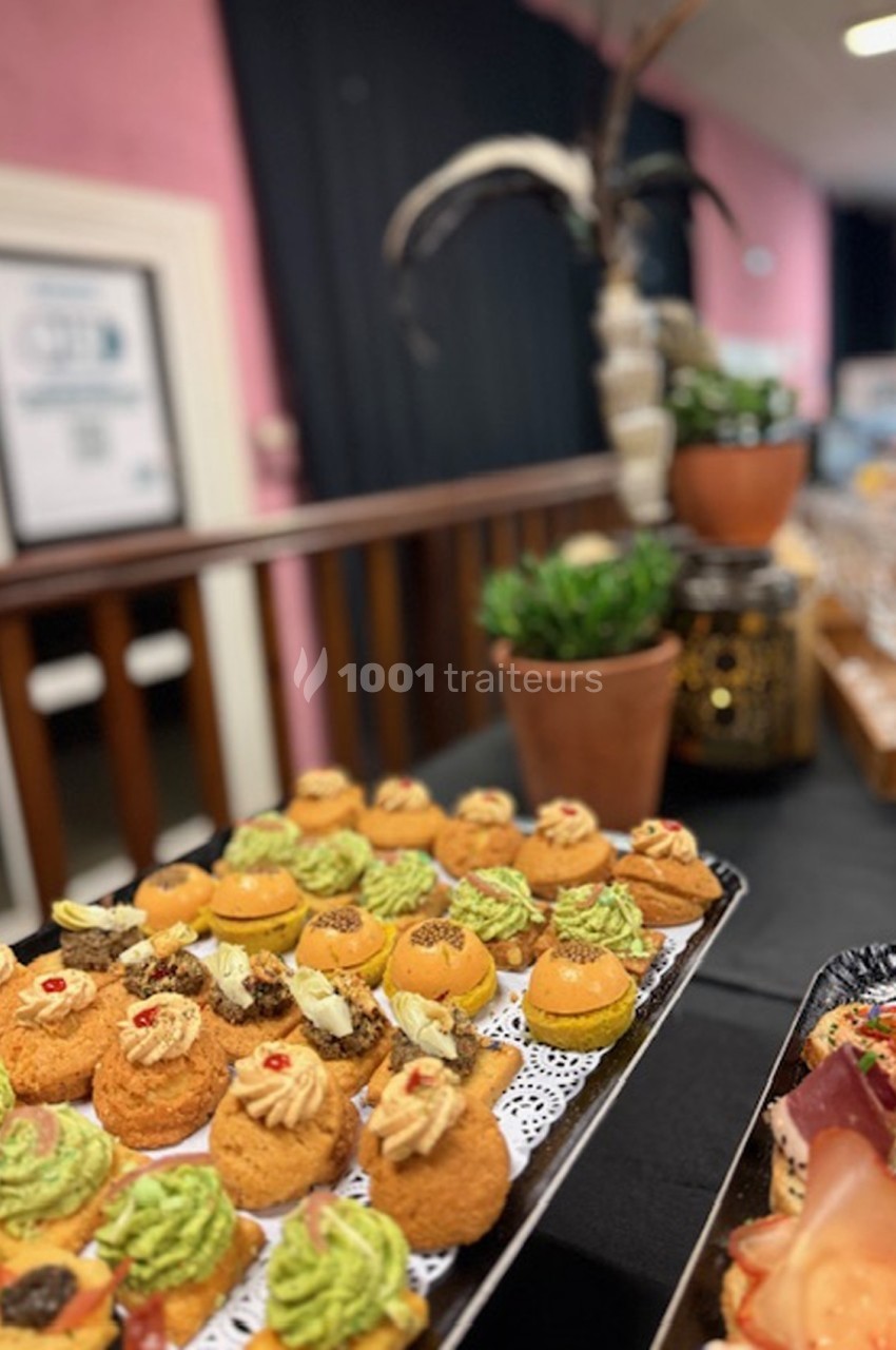 Plateau de petits fours variés avec des garnitures colorées, présenté sur une table dans un cadre intérieur.
