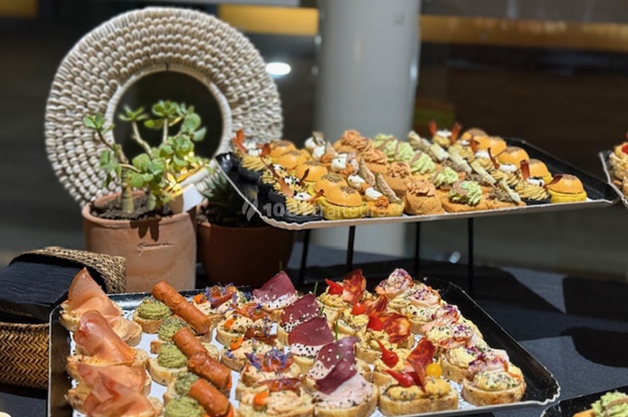 Plateaux de canapés variés avec garnitures colorées, présentés sur une table décorée de plantes et d'éléments naturels.