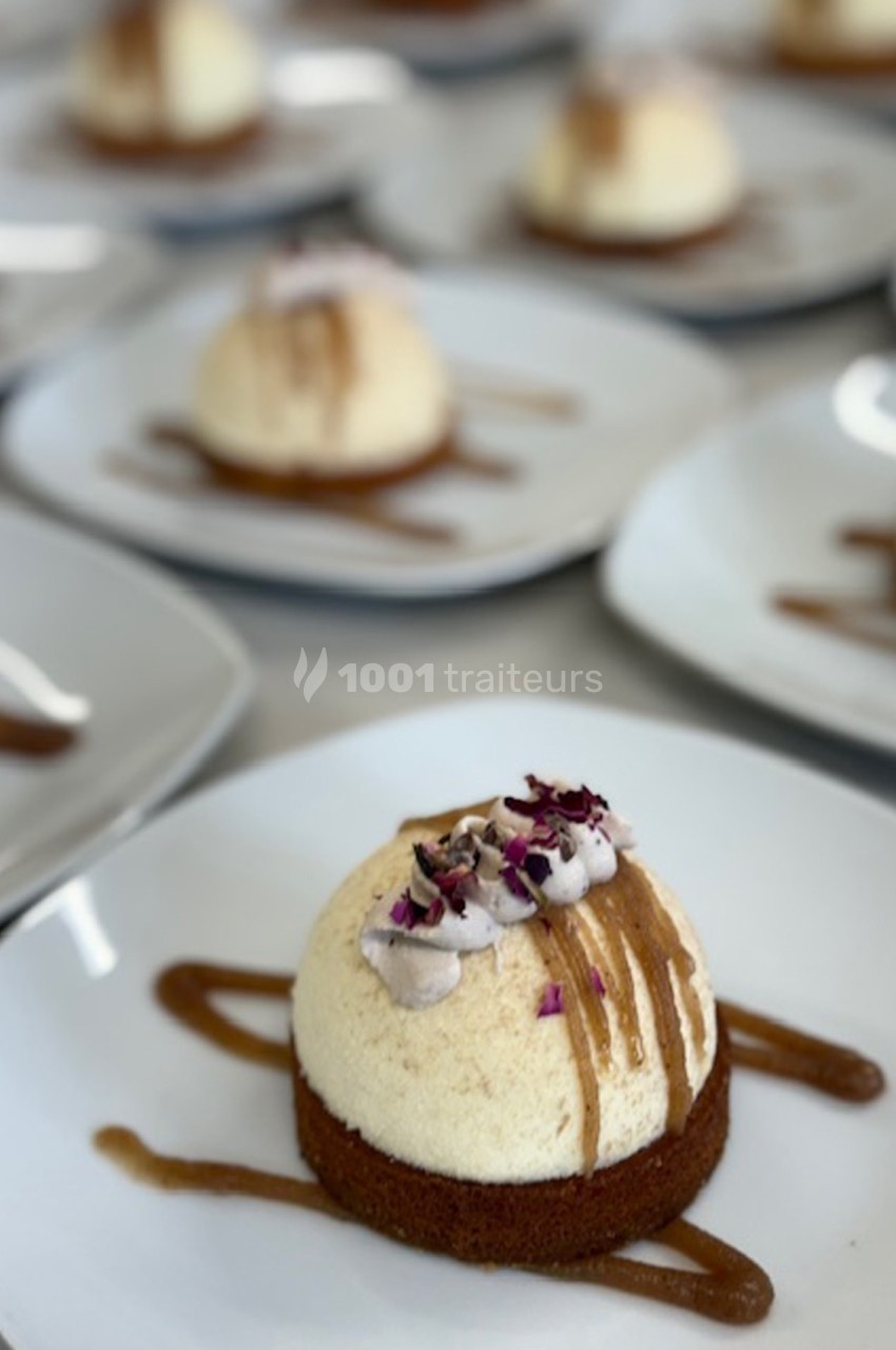 Desserts individuels sur assiettes blanches, composés d'une base biscuitée, mousse et décorations florales.