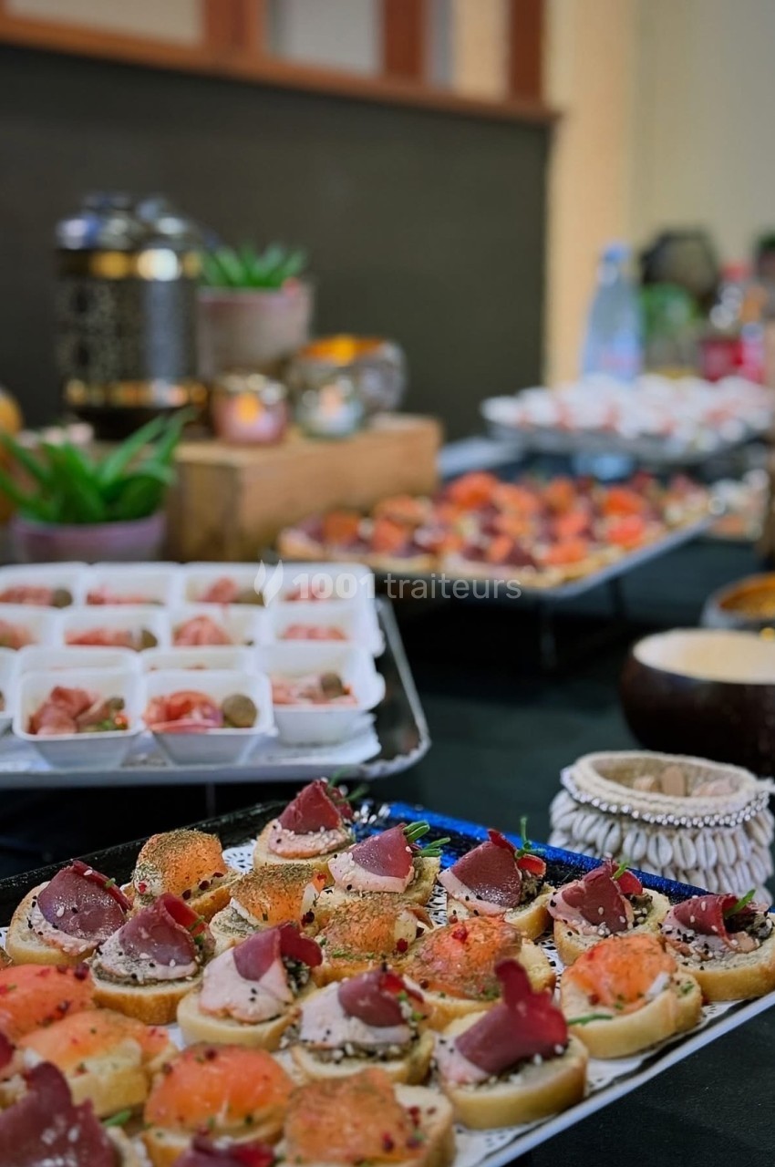 Plateau de canapés variés avec saumon, jambon et garnitures, présenté sur une table de buffet décorée.