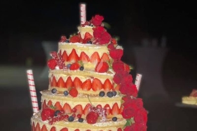 Gâteau à plusieurs étages décoré de fraises, myrtilles et roses rouges, avec des pailles en décoration.