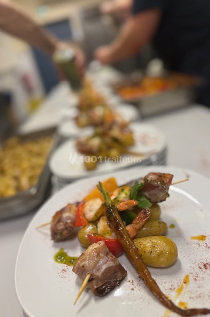 Assiettes garnies de brochettes de viande et légumes, accompagnées de pommes de terre, alignées sur un plan de travail.