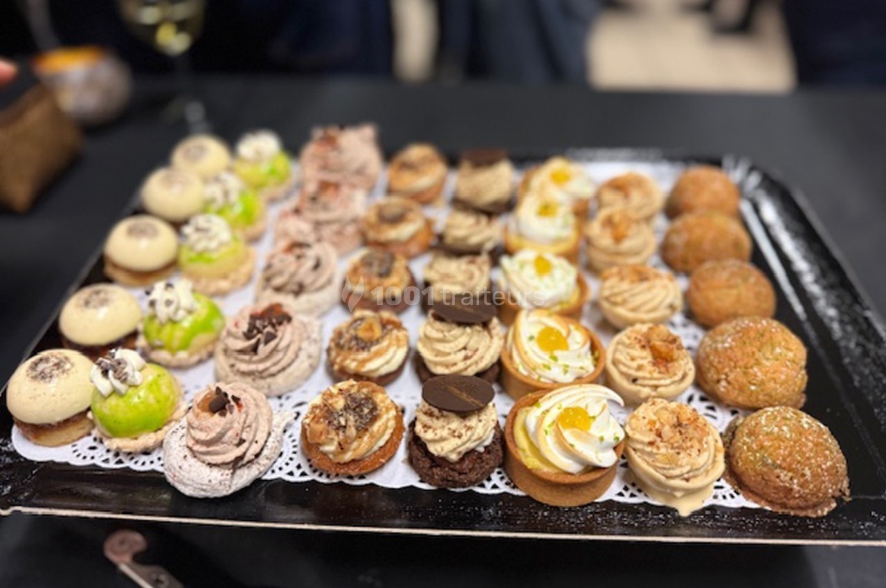 Plateau de mignardises variées disposées sur une nappe noire, comprenant des desserts sucrés et colorés.
