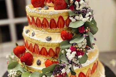 Gâteau à plusieurs étages décoré de fraises, myrtilles et roses rouges, avec des pailles en décoration.