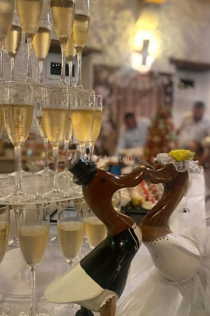 Tour de coupes de champagne avec au premier plan deux figurines de cigognes en tenue de mariage s'embrassant.