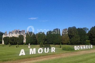 Salle de réception décorée avec des tables rondes, nappes blanches, chaises assorties et ornements dorés.