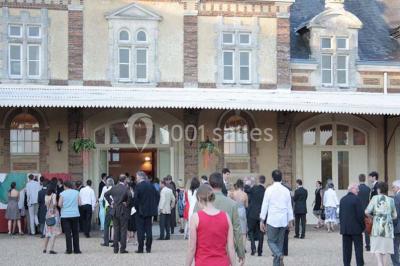 Salle de réception décorée avec des tables rondes, nappes blanches, chaises assorties et ornements dorés.