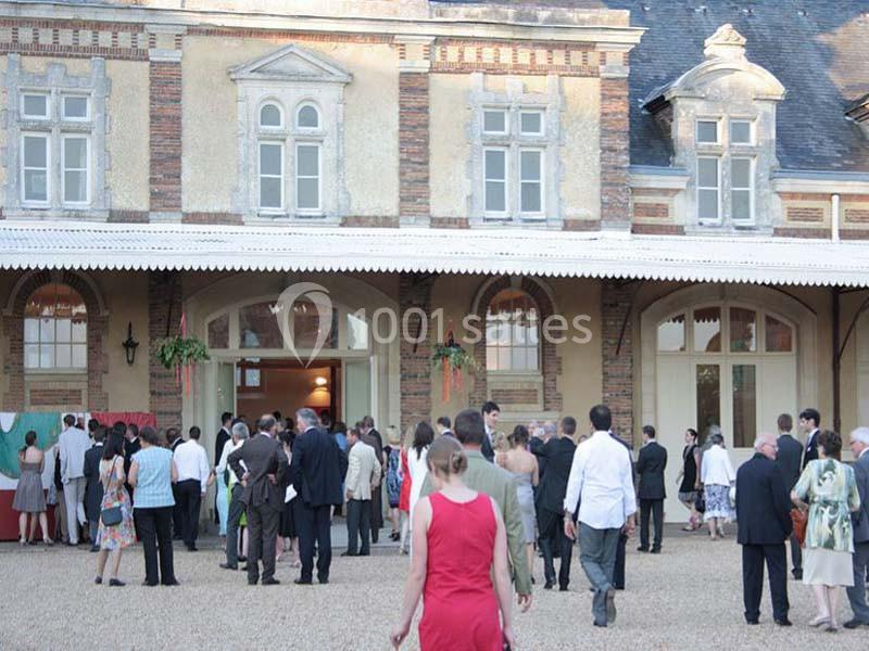 Groupe de personnes rassemblées devant un bâtiment ancien avec des fenêtres en arc et des murs en briques.
