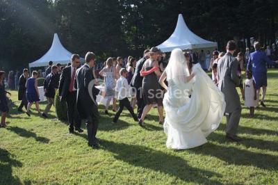 Salle de réception décorée avec des tables rondes, nappes blanches, chaises assorties et ornements dorés.