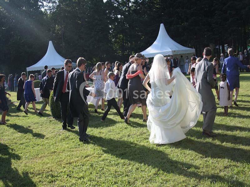 Groupe de personnes marchant sur une pelouse lors d'une réception en plein air avec des tentes blanches en arrière-plan.