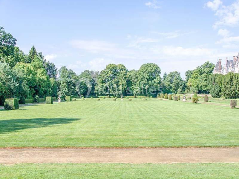 Pelouse bien entretenue entourée d'arbres et de buissons, sous un ciel dégagé.