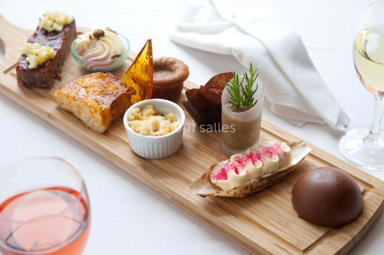 Plateau en bois avec divers desserts raffinés, incluant gâteaux, mousses, crumble et décorations gourmandes.