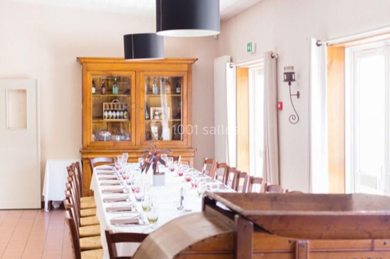 Salle à manger lumineuse avec une grande table dressée, entourée de chaises, et un buffet en bois en arrière-plan.
