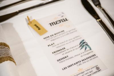 Table décorée pour un mariage avec livre d'or, lettres dorées, lampion rose et panneau en carton dans un cadre verdoyant.