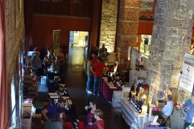 Vue d'un marché couvert avec des stands de produits locaux, des visiteurs et une architecture en pierre et bois.