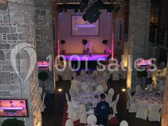 Salle de réception avec tables dressées et scène éclairée pour une présentation ou un spectacle.