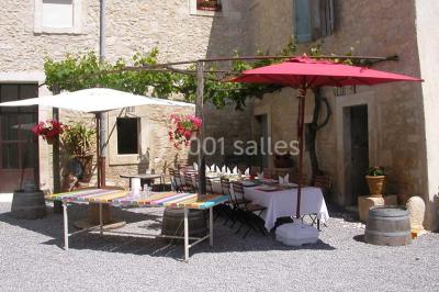 Salle de réception avec une longue table dressée, nappes blanches, vaisselle élégante et décorations florales.