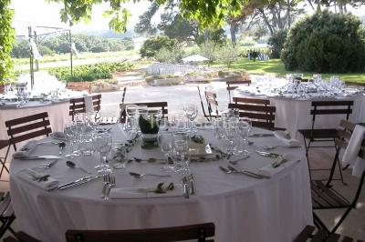 Salle de réception avec une longue table dressée, nappes blanches, vaisselle élégante et décorations florales.