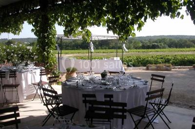 Salle de réception avec une longue table dressée, nappes blanches, vaisselle élégante et décorations florales.