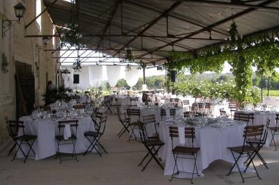 Salle de réception avec une longue table dressée, nappes blanches, vaisselle élégante et décorations florales.