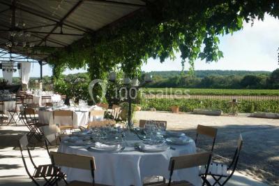Salle de réception avec une longue table dressée, nappes blanches, vaisselle élégante et décorations florales.