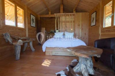 Salle de réception avec une longue table dressée, nappes blanches, vaisselle élégante et décorations florales.