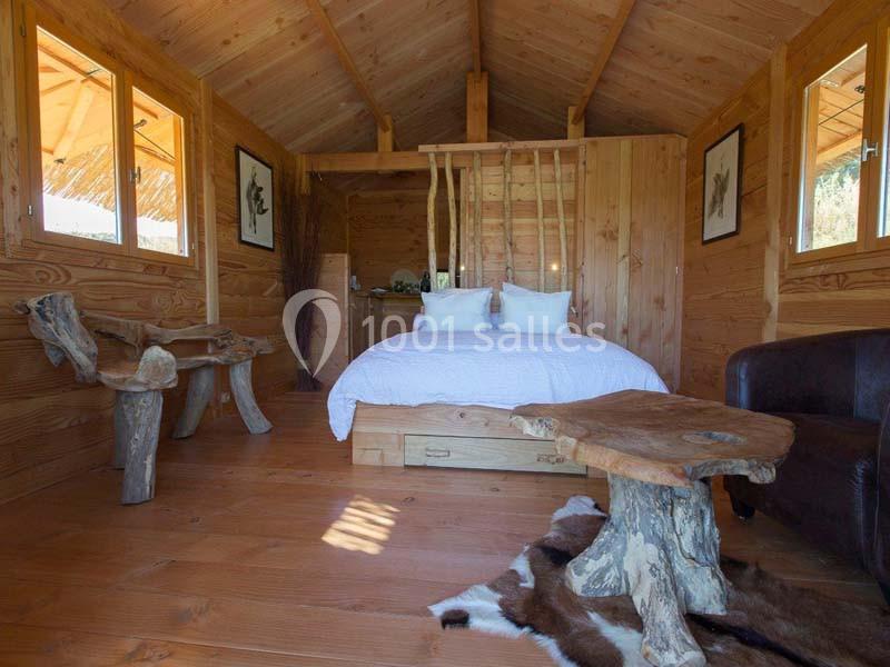 Intérieur d'une cabane en bois avec un lit double, mobilier rustique et décoration naturelle.