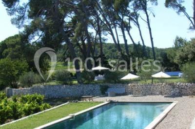 Salle de réception avec une longue table dressée, nappes blanches, vaisselle élégante et décorations florales.