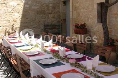 Salle de réception avec une longue table dressée, nappes blanches, vaisselle élégante et décorations florales.