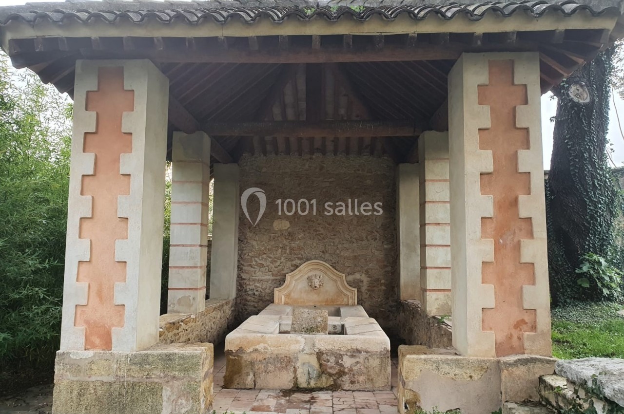 Abri en pierre et bois abritant un ancien lavoir avec deux bassins, entouré de végétation.