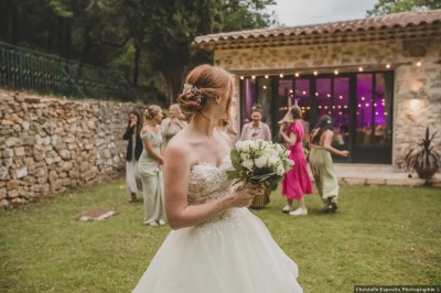 Miniature Location salle Méounes-lès-Montrieux (Var) - La Source #3 Une jeune fille en robe blanche porte un coussin sur une allée décorée lors d'une cérémonie en plein air.