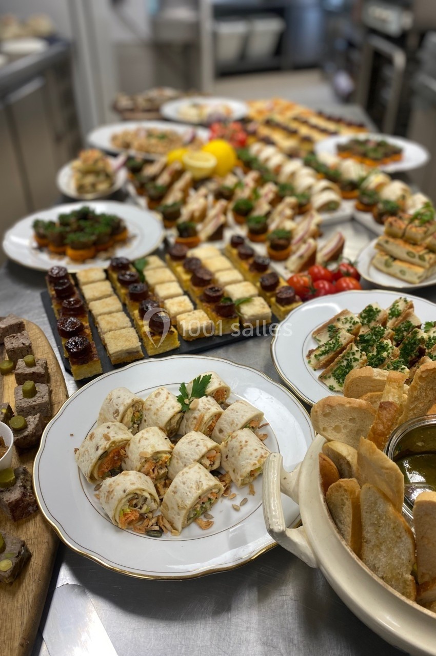 Buffet varié composé de bouchées salées, wraps, toasts et dips, présenté sur une table en cuisine.
