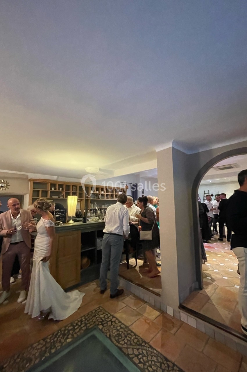 Des invités discutent dans une salle de réception avec un bar, lors d'un événement festif en intérieur.