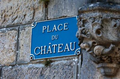 Clocher en pierre avec toit en ardoise sous un ciel bleu, la lune visible en arrière-plan.