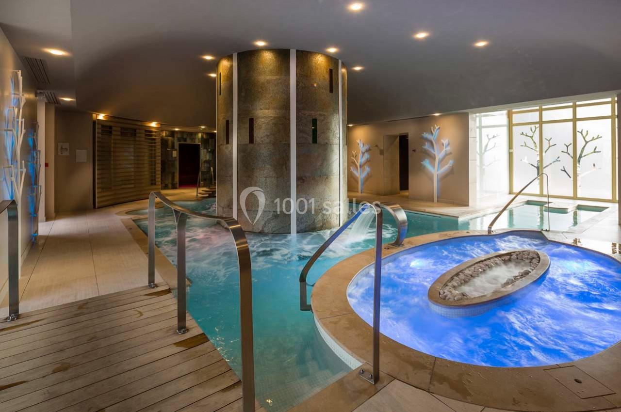 Bassin d'hydrothérapie avec jets d'eau, bain à remous et éclairage tamisé dans un espace intérieur moderne.