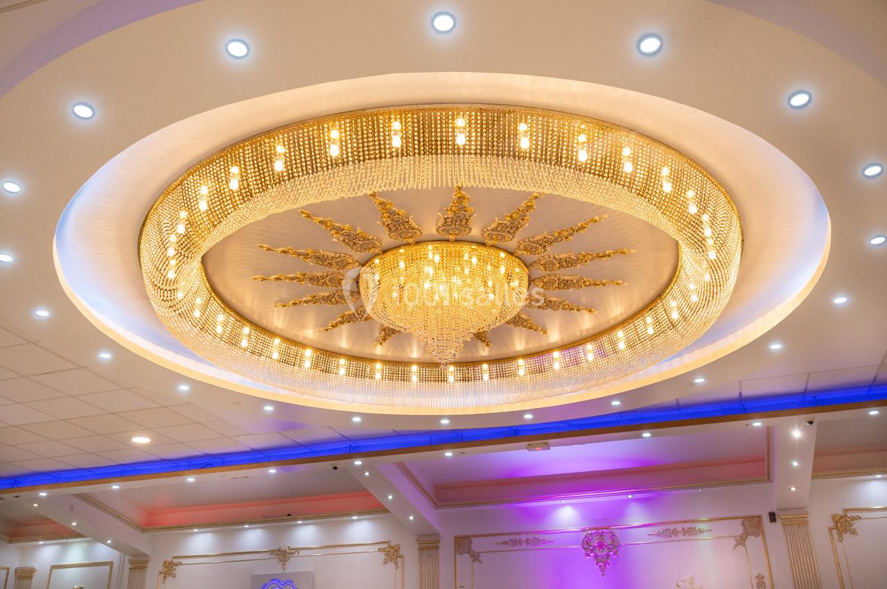 Plafonnier circulaire doré avec lustre central en cristal, entouré de lumières LED dans une salle élégante.