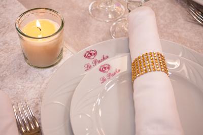 Salle de réception décorée avec un canapé doré, des arbres fleuris et un éclairage rose sur une estrade blanche.