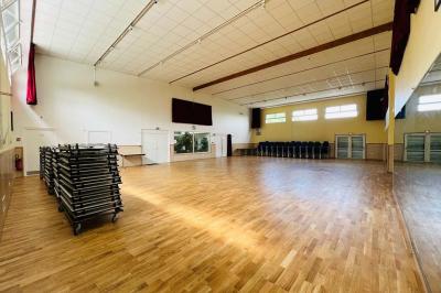 Schéma d'un bâtiment avec une grande salle centrale, quatre petites salles et trois entrées distinctes indiquées.